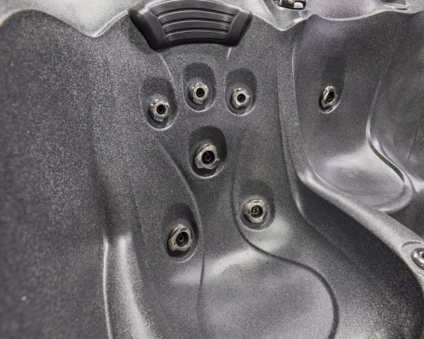 Close-up of a hot tub interior showing multiple water jets and a sculpted seating area.